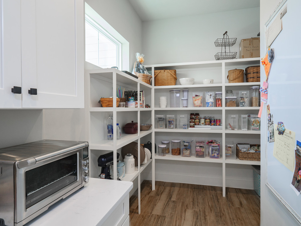 Inspiration for a large country u-shaped kitchen pantry in Jacksonville with a farmhouse sink, shaker cabinets, white cabinets, quartz benchtops, white splashback, subway tile splashback, stainless steel appliances, porcelain floors, with island, brown floor and white benchtop.