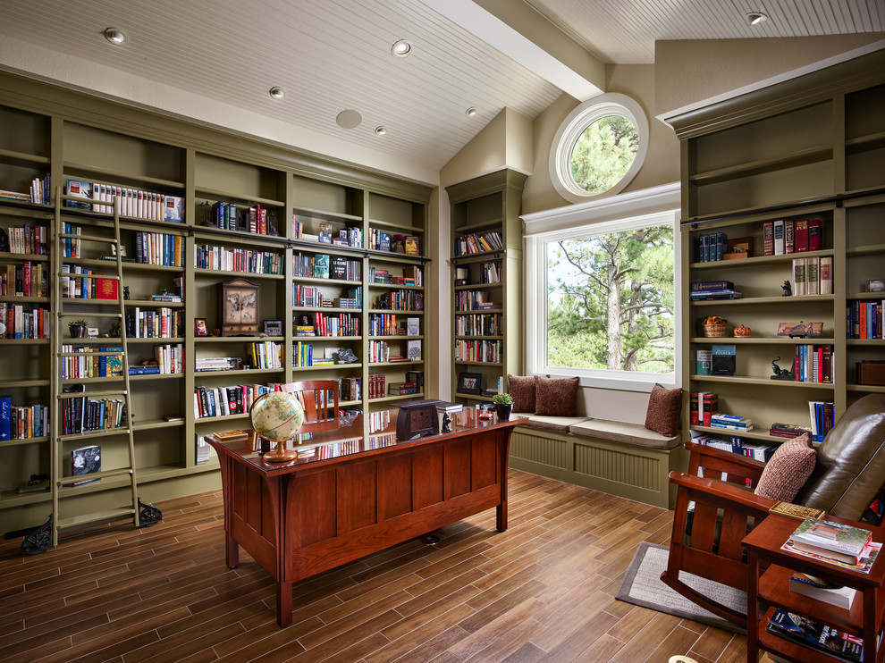 This is an example of an arts and crafts home office in Denver with a library, green walls, no fireplace and a freestanding desk.