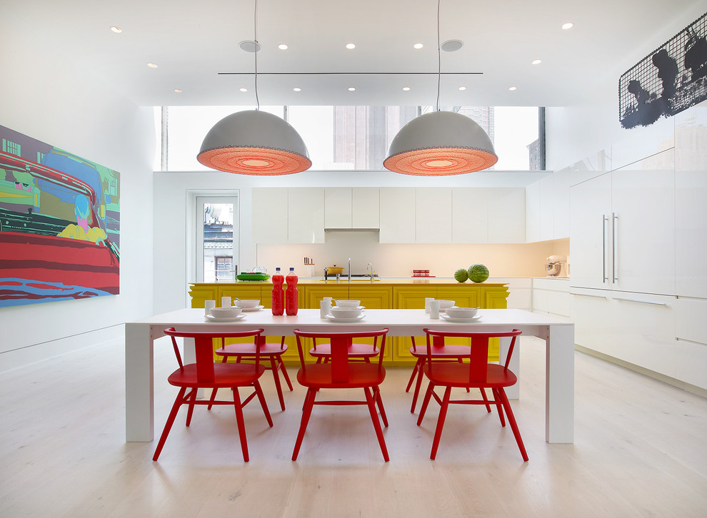 Photo of a large contemporary l-shaped eat-in kitchen in New York with white splashback, light hardwood floors, with island, flat-panel cabinets, white cabinets and panelled appliances.
