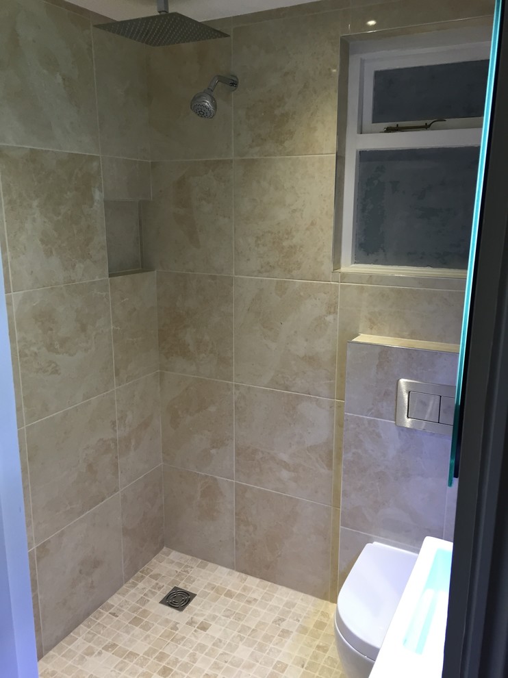 Photo of a small contemporary bathroom in London with a wall-mount sink, an open shower, a wall-mount toilet, beige walls and travertine floors.