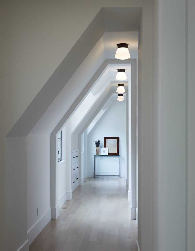 Photo of a transitional hallway in Minneapolis with white walls, light hardwood floors and beige floor.