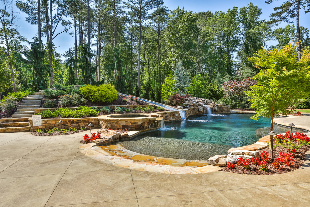 Inspiration for a large tropical backyard custom-shaped natural pool in Atlanta with a water slide and stamped concrete.