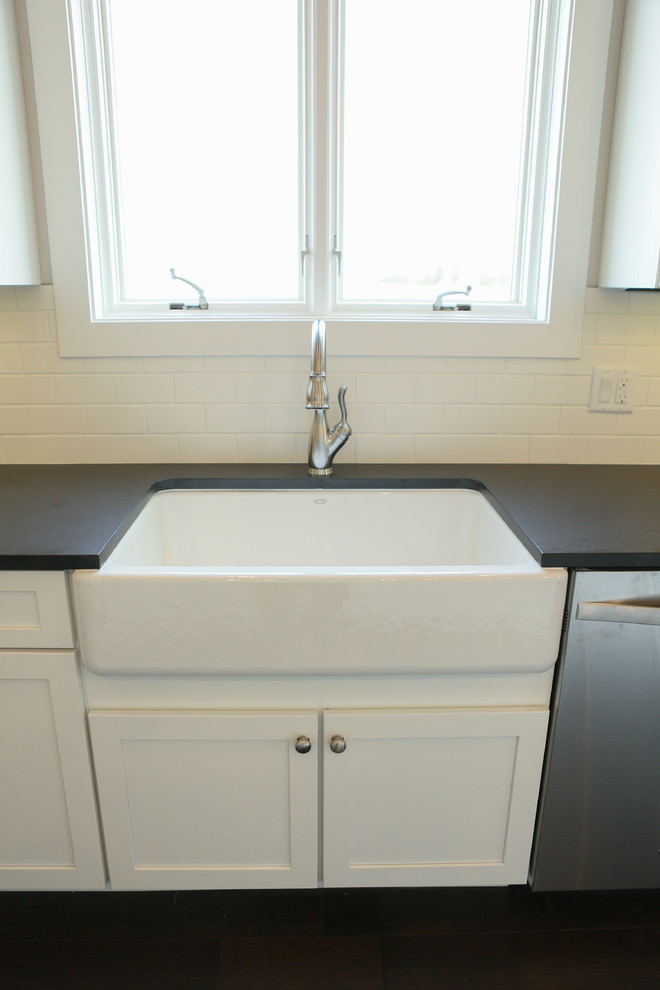 Example of a large transitional u-shaped dark wood floor home design design in Chicago with a farmhouse sink, shaker cabinets, yellow cabinets, granite countertops, white backsplash, subway tile backsplash, stainless steel appliances and an island