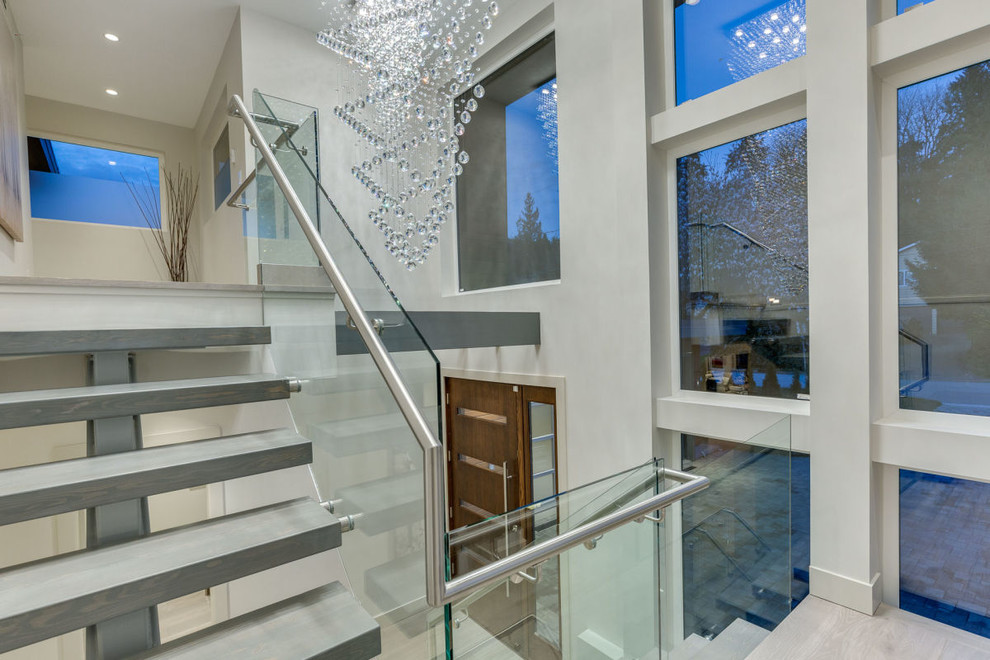 This is an example of a mid-sized contemporary wood u-shaped staircase in Vancouver with open risers and glass railing.