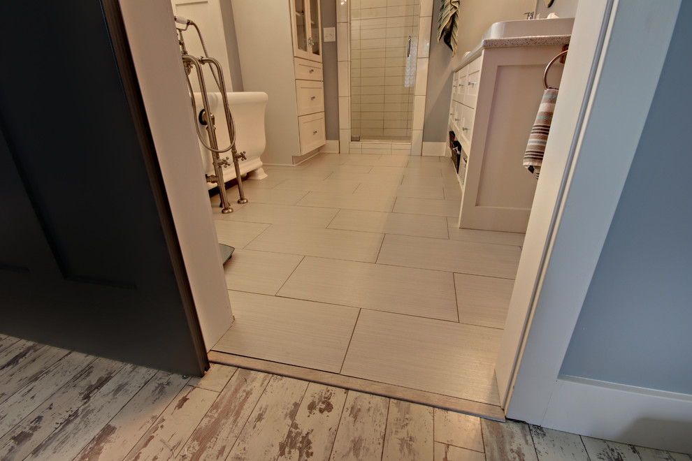 This is an example of a mid-sized contemporary master bathroom in Grand Rapids with recessed-panel cabinets, white cabinets, a claw-foot tub, a double shower, white walls, porcelain floors, a vessel sink, engineered quartz benchtops, white floor and a hinged shower door.