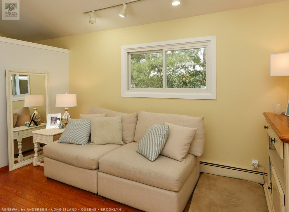 Imagen de sala de estar con biblioteca abierta pequeña sin chimenea y televisor con paredes amarillas y suelo de madera en tonos medios