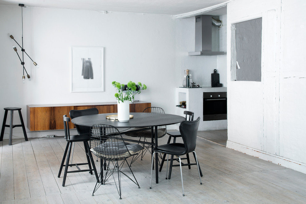 This is an example of a mid-sized scandinavian kitchen/dining combo in Copenhagen with white walls, light hardwood floors and no fireplace.