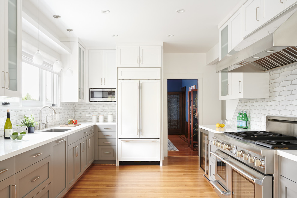 Inspiration for a transitional u-shaped separate kitchen in San Francisco with an undermount sink, shaker cabinets, grey cabinets, white splashback, ceramic splashback, stainless steel appliances, medium hardwood floors, no island, beige floor and white benchtop.