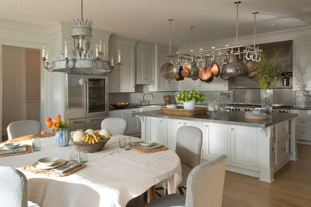Inspiration for a large traditional u-shaped kitchen in New York with a drop-in sink, white cabinets, stainless steel appliances, light hardwood floors and with island.