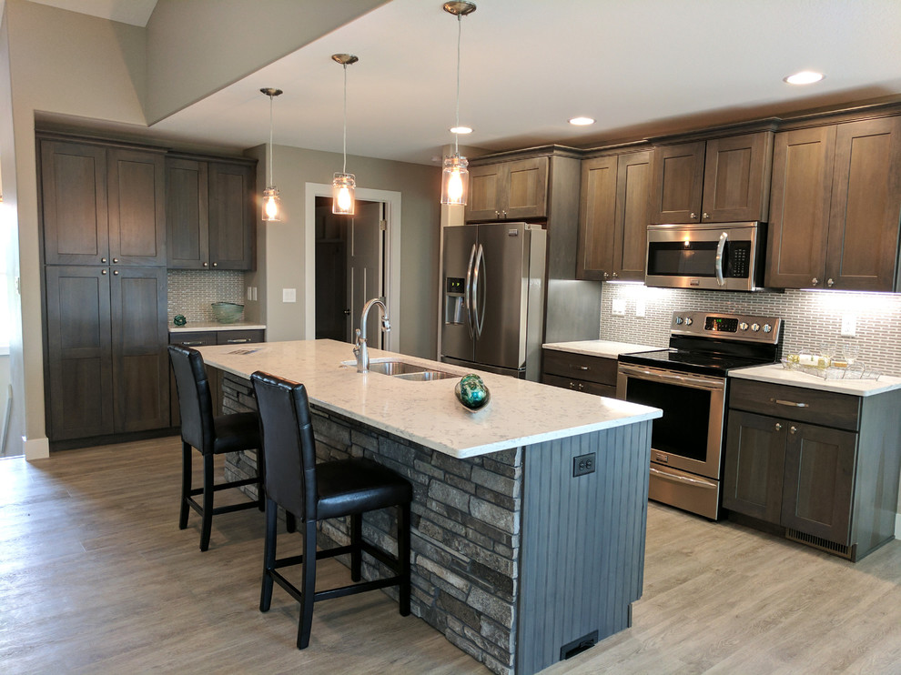 Inspiration for a mid-sized rustic galley laminate floor and beige floor open concept kitchen remodel in Cedar Rapids with a double-bowl sink, shaker cabinets, dark wood cabinets, quartz countertops, gray backsplash, matchstick tile backsplash, stainless steel appliances and an island