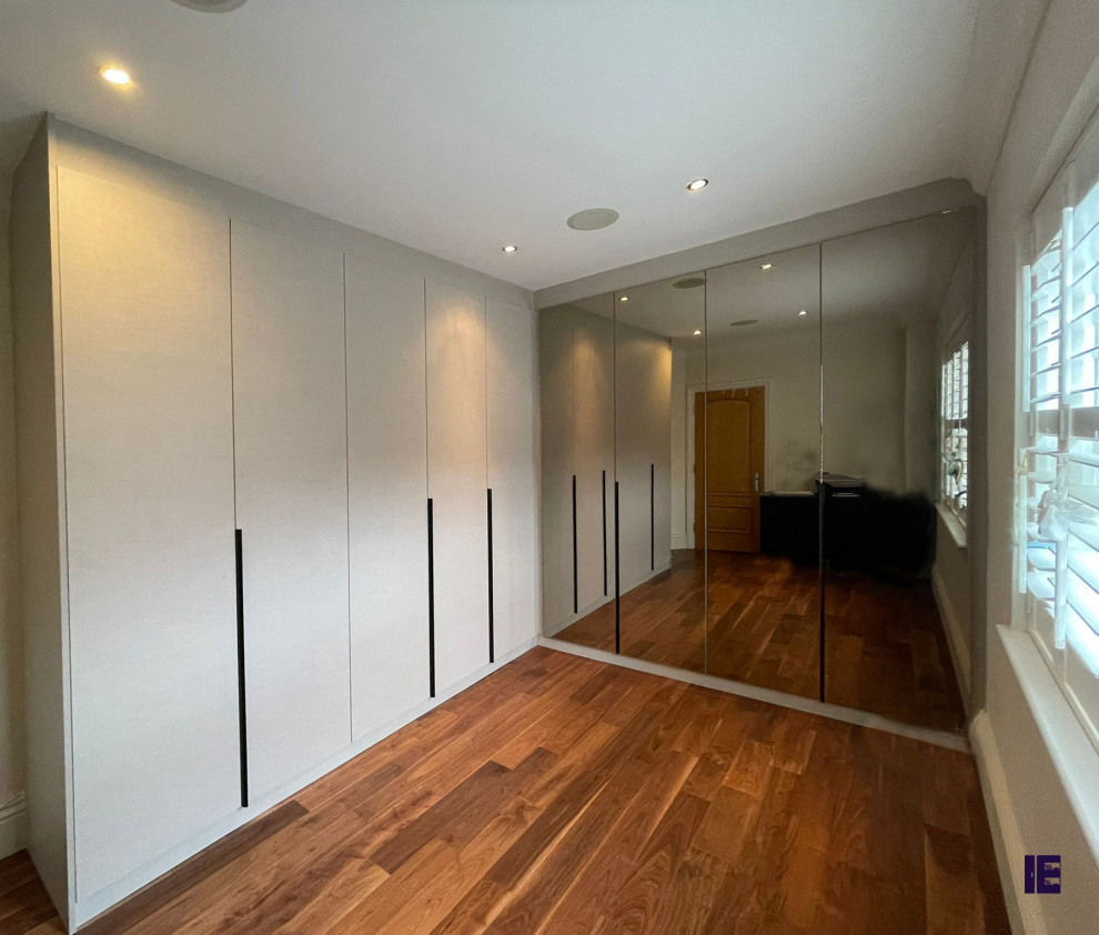 Kleines Modernes Ankleidezimmer mit Einbauschrank, Glasfronten, grauen Schränken, Sperrholzboden, braunem Boden und Holzdecke in London