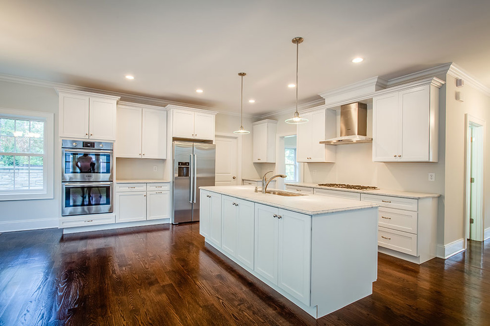 Eat-in kitchen - large transitional l-shaped dark wood floor and brown floor eat-in kitchen idea with an undermount sink, shaker cabinets, white cabinets, white backsplash, stainless steel appliances and an island
