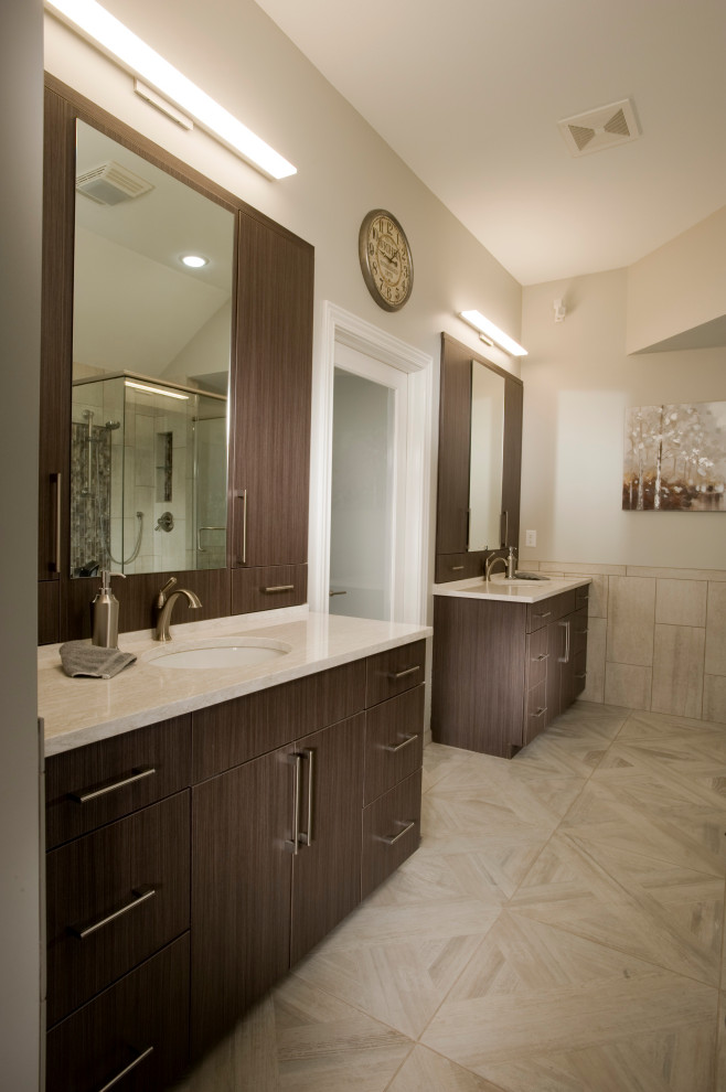 Photo of a mid-sized contemporary master bathroom in Wichita with glass-front cabinets, brown cabinets, a freestanding tub, a two-piece toilet, beige tile, porcelain tile, beige walls, porcelain floors, an undermount sink, engineered quartz benchtops, beige floor, a hinged shower door, white benchtops, a niche, a double vanity and a built-in vanity.