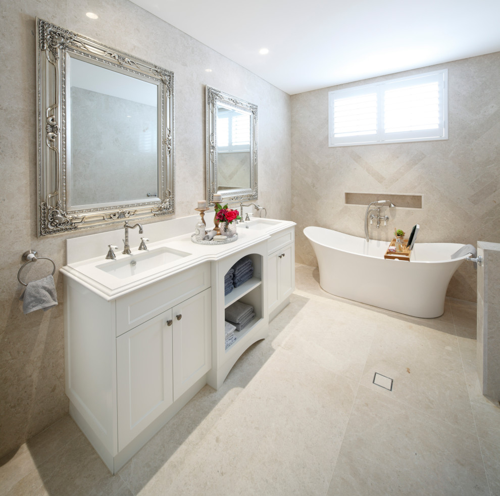 Inspiration for a traditional master bathroom in Sydney with recessed-panel cabinets, white cabinets, a freestanding tub, beige tile, marble, marble floors, engineered quartz benchtops, beige floor and white benchtops.