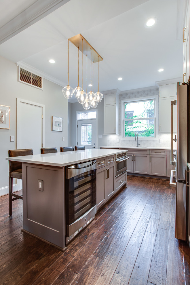 Inspiration for a large transitional l-shaped medium tone wood floor and brown floor eat-in kitchen remodel in DC Metro with an undermount sink, shaker cabinets, white cabinets, solid surface countertops, white backsplash, ceramic backsplash, stainless steel appliances, an island and white countertops
