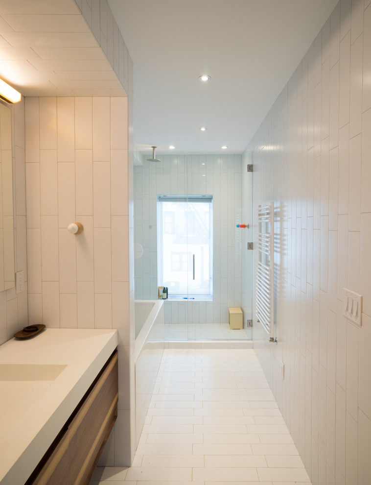 Inspiration for a mid-sized modern master bathroom in New York with flat-panel cabinets, brown cabinets, a corner tub, an alcove shower, a one-piece toilet, white tile, ceramic tile, white walls, ceramic floors, an integrated sink, quartzite benchtops, white floor and a hinged shower door.