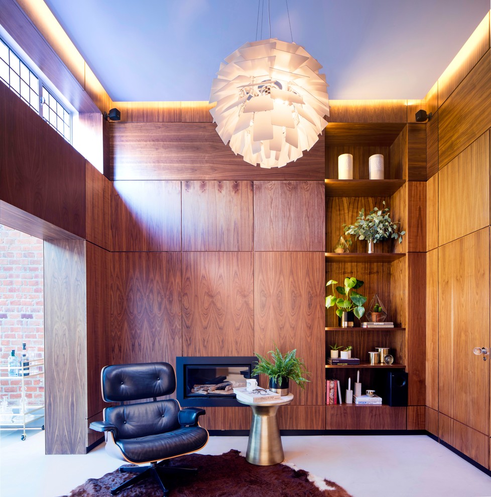 This is an example of a mid-sized midcentury home office in London with brown walls, concrete floors and a ribbon fireplace.