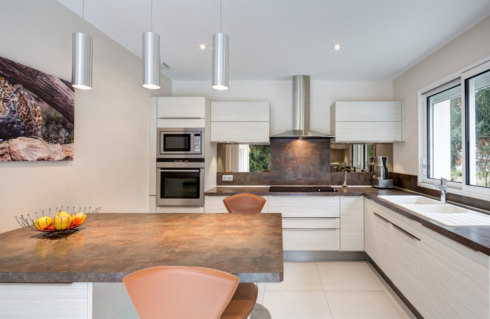 Photo of a large contemporary l-shaped eat-in kitchen in Paris with a double-bowl sink, white cabinets, brown splashback, stainless steel appliances and with island.