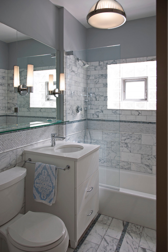 Tub/shower combo - mid-sized transitional master gray tile and stone tile marble floor tub/shower combo idea in Chicago with flat-panel cabinets, white cabinets, a two-piece toilet, gray walls, an undermount sink and quartz countertops