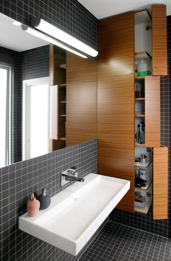 This is an example of a contemporary bathroom in Sydney with black tile, mosaic tile and a trough sink.