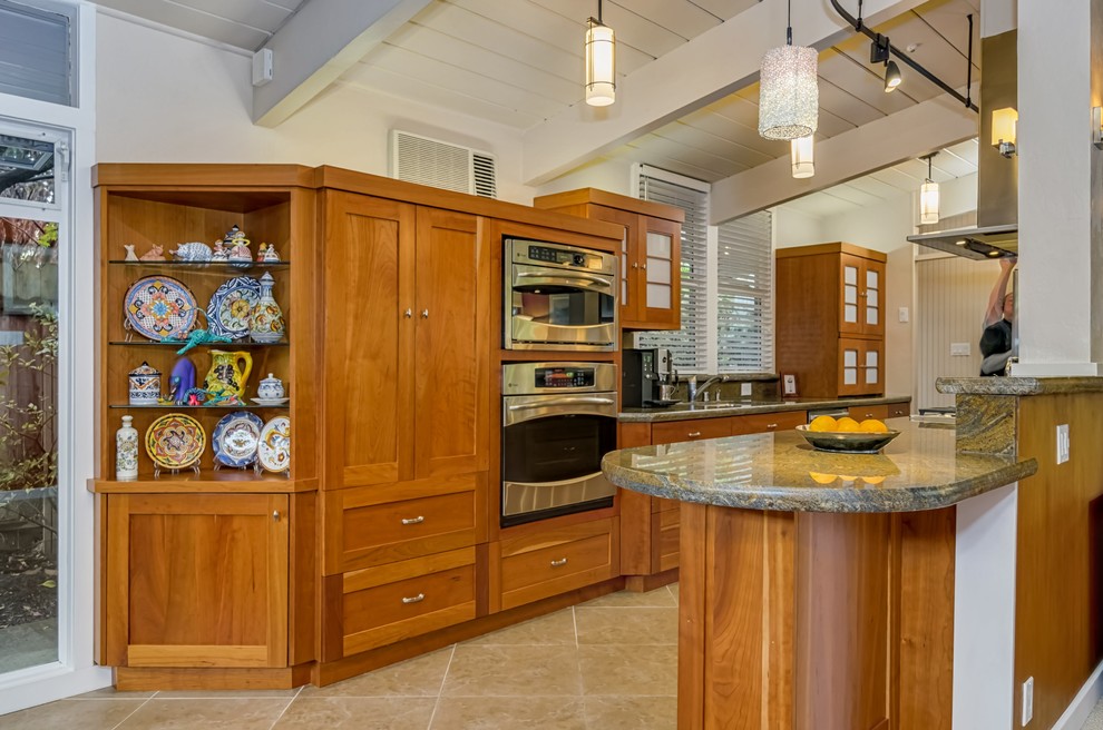 This is an example of a midcentury galley open plan kitchen in San Francisco with an undermount sink, shaker cabinets, medium wood cabinets, granite benchtops, brown splashback, stone slab splashback, stainless steel appliances, porcelain floors, a peninsula, brown floor and brown benchtop.