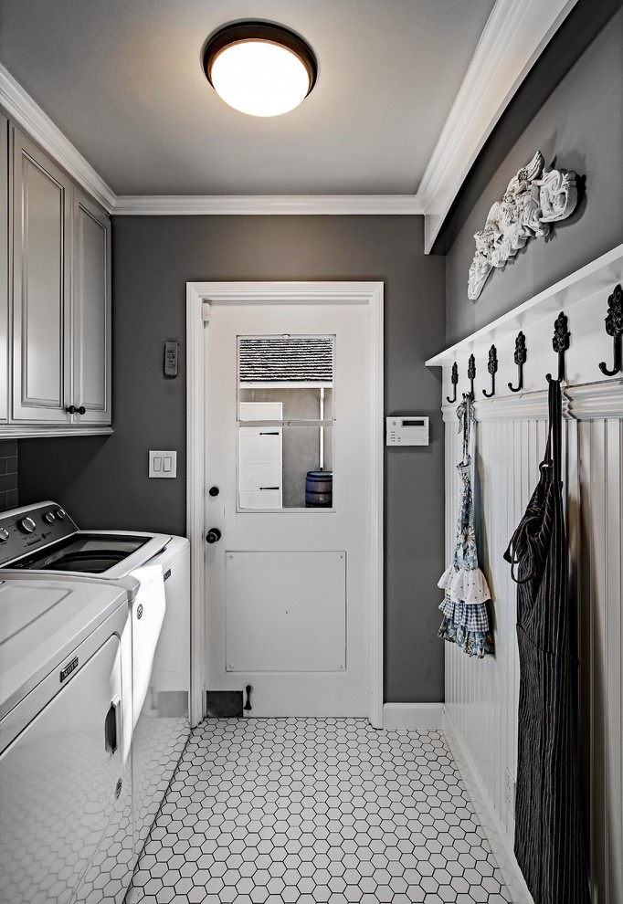 Inspiration for a mid-sized transitional single-wall dedicated laundry room in Orange County with raised-panel cabinets, grey cabinets, grey walls, porcelain floors, a side-by-side washer and dryer and white floor.