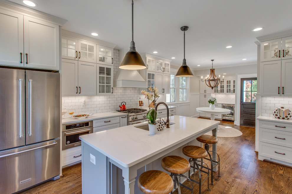Design ideas for a large transitional eat-in kitchen in DC Metro with an undermount sink, shaker cabinets, white cabinets, quartz benchtops, white splashback, stainless steel appliances, with island, brown floor, white benchtop, subway tile splashback and dark hardwood floors.