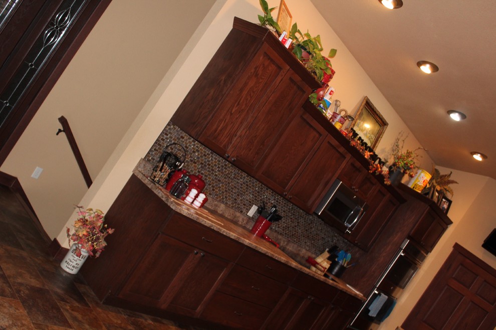 Example of a large transitional single-wall slate floor and beige floor enclosed kitchen design with shaker cabinets, dark wood cabinets, limestone countertops, beige backsplash, mosaic tile backsplash, stainless steel appliances and no island