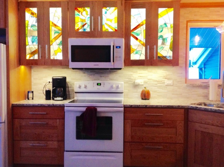 Enclosed kitchen - mid-sized transitional u-shaped medium tone wood floor enclosed kitchen idea with an undermount sink, shaker cabinets, dark wood cabinets, granite countertops, gray backsplash, stone tile backsplash, white appliances and no island