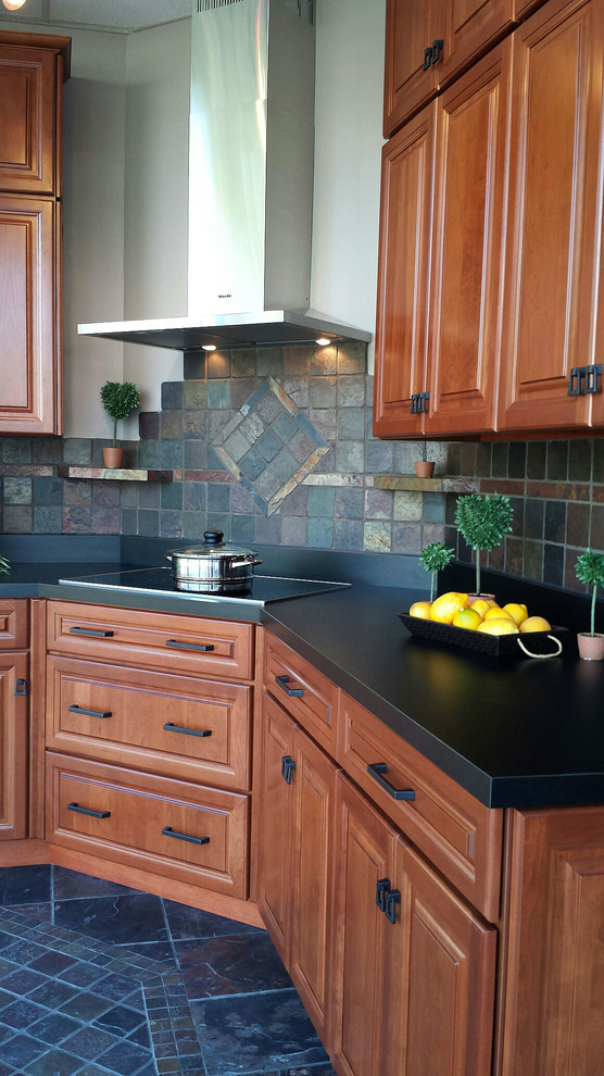 Inspiration for a mid-sized rustic l-shaped slate floor enclosed kitchen remodel with medium tone wood cabinets, laminate countertops, multicolored backsplash, stone tile backsplash, black appliances, no island and raised-panel cabinets