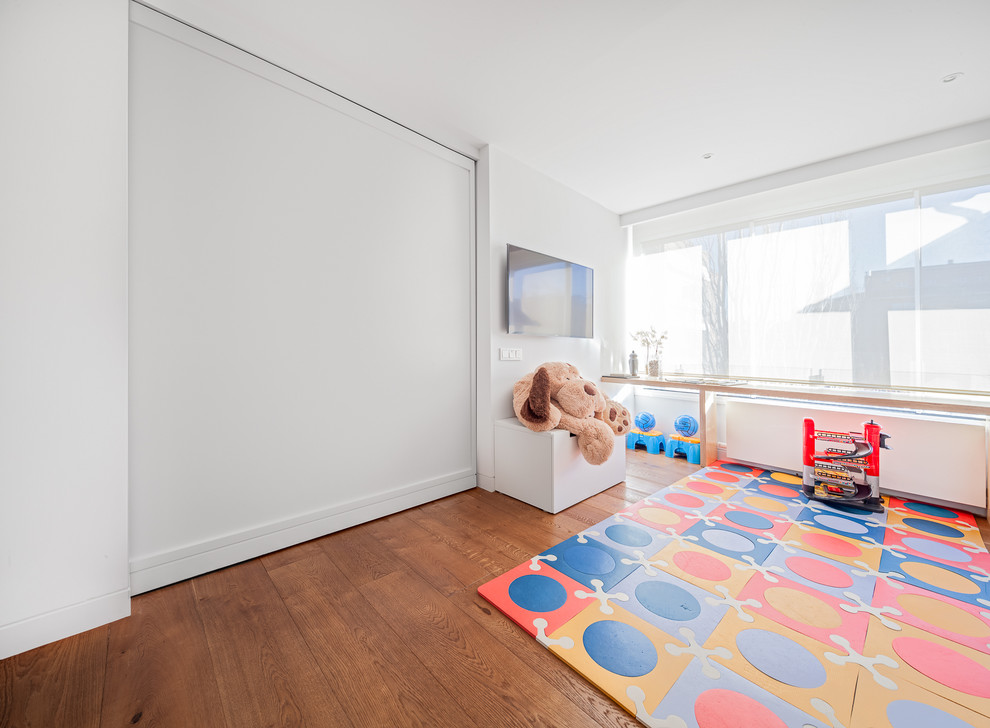 This is an example of a large contemporary gender-neutral kids' playroom for kids 4-10 years old in Madrid with white walls and medium hardwood floors.