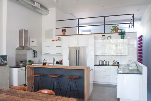 High-gloss white kitchen cabinet doors with glass-front uppers in a modern loft, reflecting light to expand the space