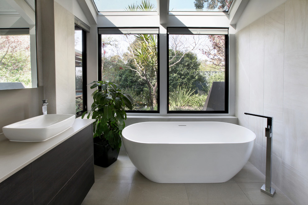 Inspiration for a mid-sized contemporary bathroom in Perth with flat-panel cabinets, dark wood cabinets, a freestanding tub, beige tile, beige walls, a vessel sink, beige floor and beige benchtops.