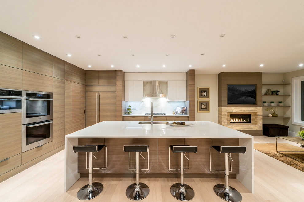 Inspiration for a large contemporary l-shaped open plan kitchen in Vancouver with an undermount sink, flat-panel cabinets, light wood cabinets, solid surface benchtops, white splashback, stone slab splashback, stainless steel appliances, light hardwood floors and with island.