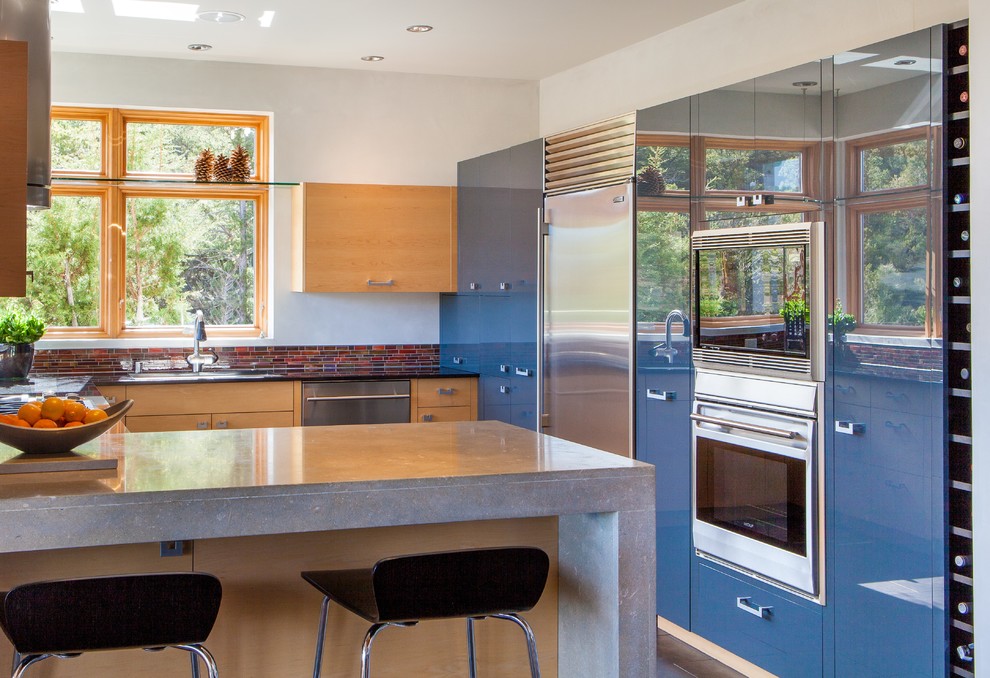 Photo of a mid-sized modern u-shaped eat-in kitchen in Albuquerque with a double-bowl sink, flat-panel cabinets, light wood cabinets, concrete benchtops, grey splashback, matchstick tile splashback, coloured appliances, dark hardwood floors and no island.