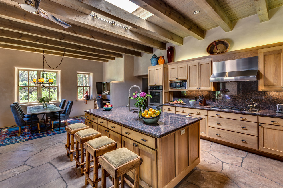 This is an example of a mid-sized l-shaped eat-in kitchen in Albuquerque with shaker cabinets, medium wood cabinets, stainless steel appliances, with island, an undermount sink, granite benchtops, blue splashback, stone tile splashback and beige floor.