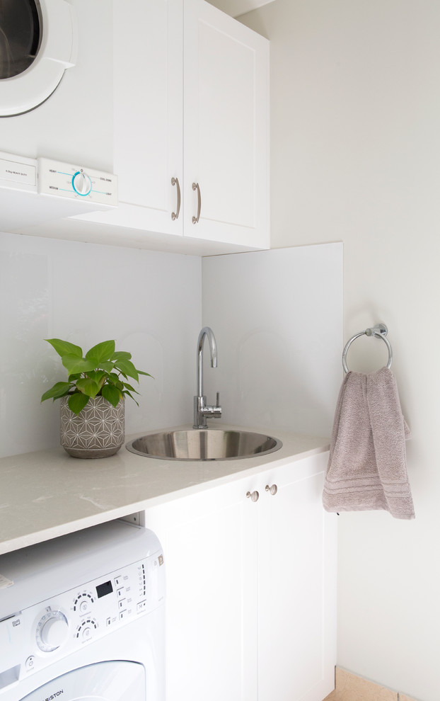 Inspiration for a small traditional single-wall dedicated laundry room in Gold Coast - Tweed with a drop-in sink, shaker cabinets, white cabinets, quartz benchtops, grey walls, ceramic floors and a stacked washer and dryer.