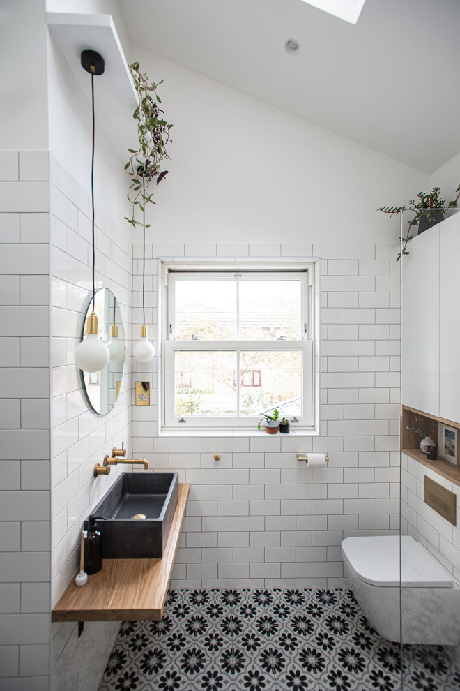 Inspiration for a medium sized scandi shower room bathroom in London with light wood cabinets, a walk-in shower, a wall mounted toilet, white tiles, cement tiles, white walls, ceramic flooring, a console sink, concrete worktops, multi-coloured floors, an open shower, grey worktops, a single sink and a vaulted ceiling.