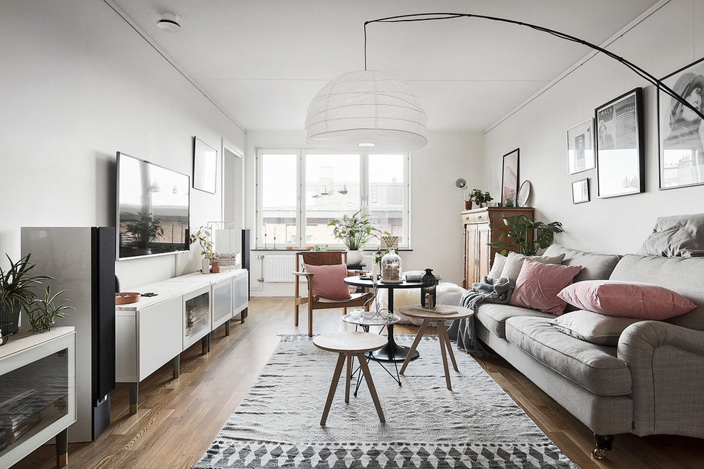 Mid-sized scandinavian formal open concept living room in Stockholm with white walls, medium hardwood floors, a wall-mounted tv and no fireplace.