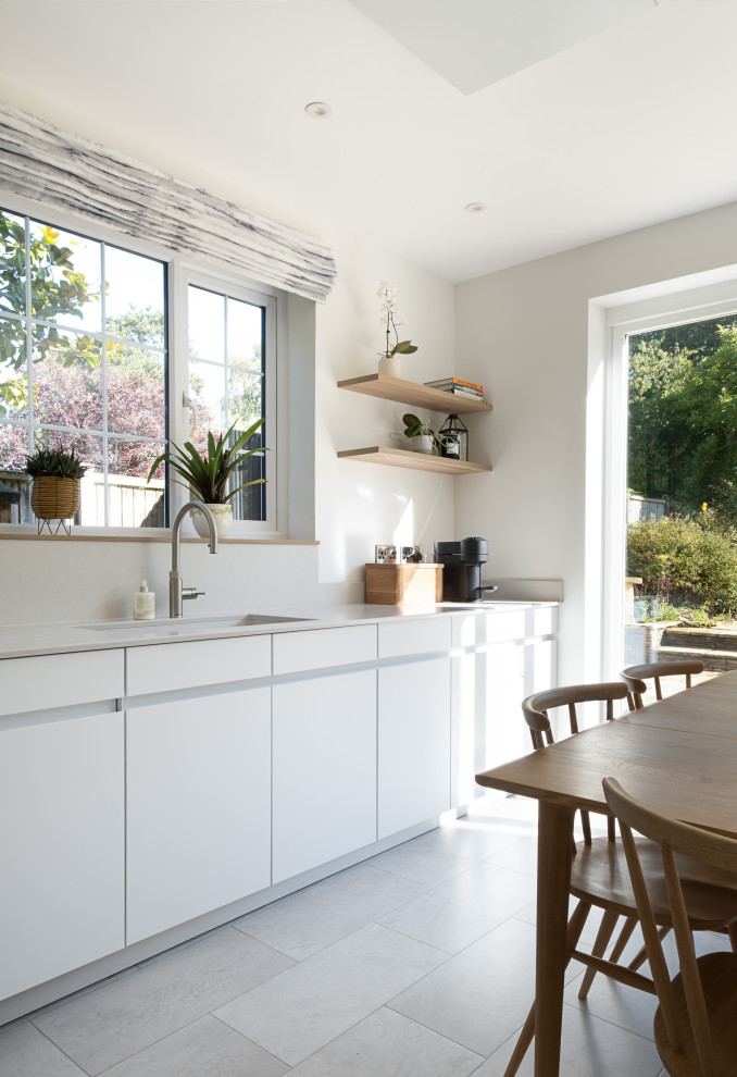Photo of a medium sized contemporary u-shaped kitchen in Gloucestershire with flat-panel cabinets, white cabinets and composite countertops.