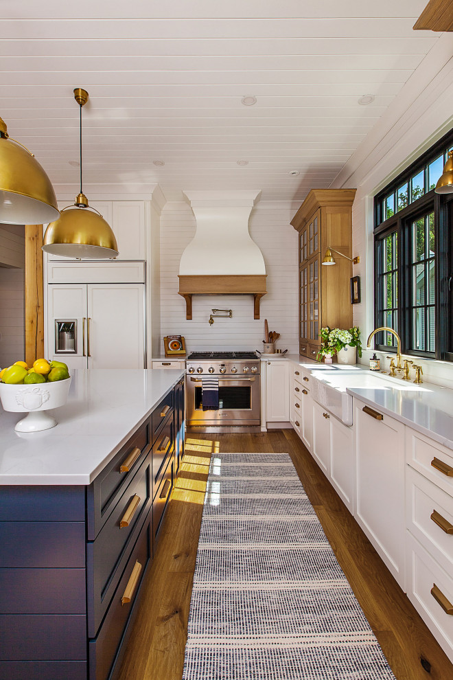 This is an example of a large beach style l-shaped open plan kitchen in Detroit with a farmhouse sink, panelled appliances, medium hardwood floors, with island and timber.