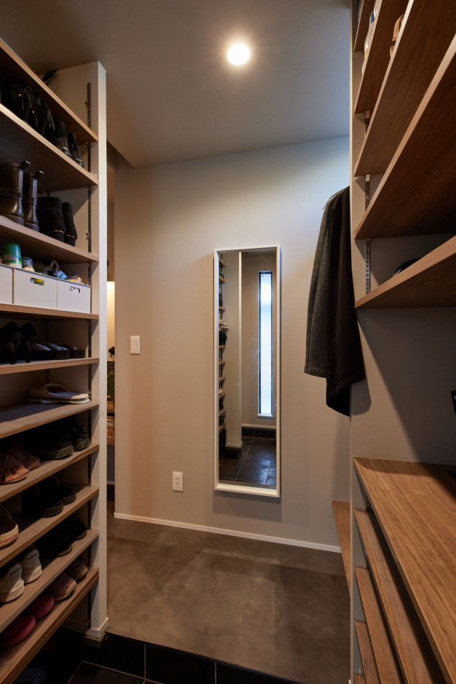Mid-sized modern walk-in wardrobe in Other with ceramic floors, black floor and wallpaper.