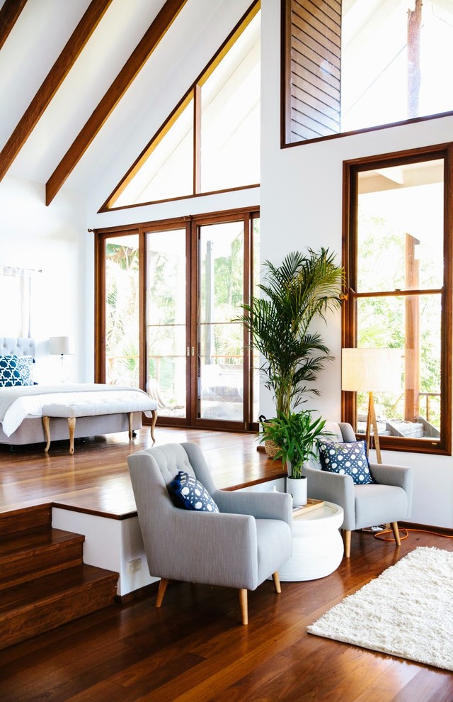 Photo of a large tropical bedroom in Other with white walls and dark hardwood floors.
