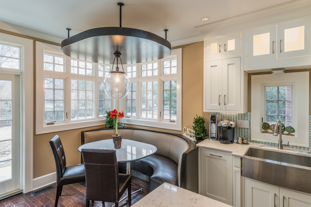 Large transitional l-shaped eat-in kitchen in Indianapolis with a farmhouse sink, shaker cabinets, white cabinets, quartz benchtops, blue splashback, mosaic tile splashback, stainless steel appliances, medium hardwood floors and a peninsula.
