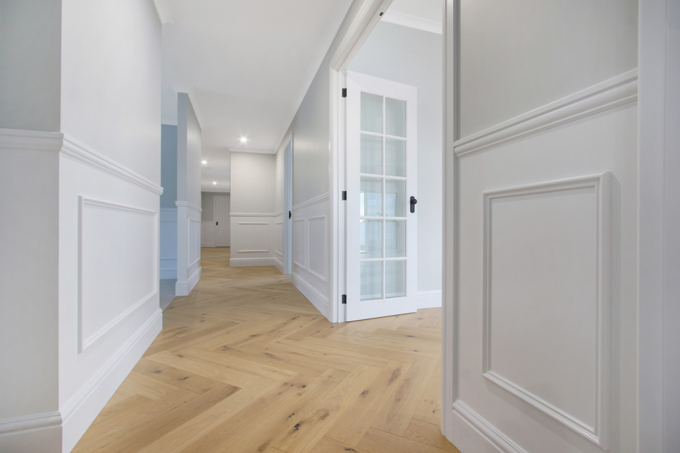 Photo of a large country hallway in Other with light hardwood floors, brown floor and decorative wall panelling.