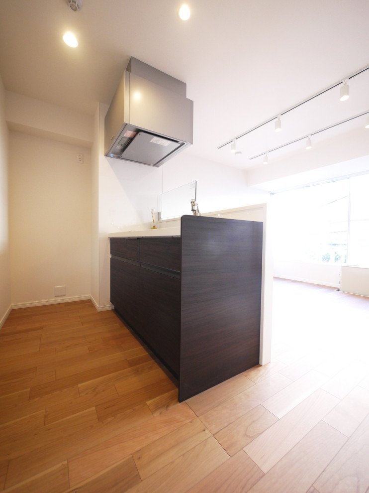 Modern single-wall open plan kitchen in Tokyo with dark wood cabinets, white splashback, plywood floors, with island, beige floor, white benchtop and wallpaper.