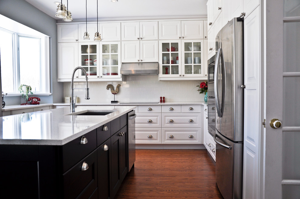 Example of a transitional eat-in kitchen design in Ottawa with an undermount sink, raised-panel cabinets, white cabinets, quartz countertops, white backsplash, porcelain backsplash, stainless steel appliances and an island