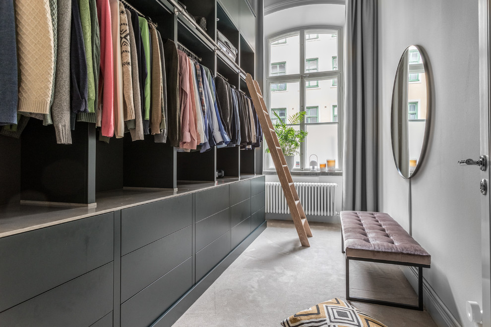 Design ideas for a large transitional gender-neutral walk-in wardrobe in Stockholm with open cabinets, black cabinets, carpet and beige floor.