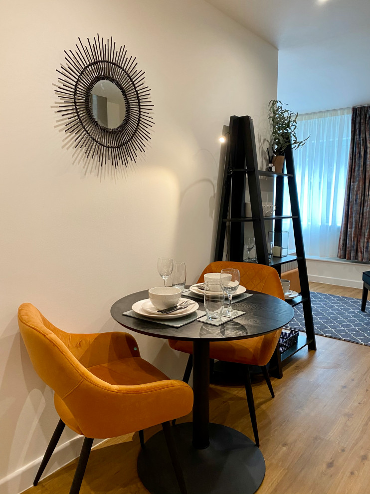 Cette image montre une petite salle à manger design avec un mur bleu, sol en stratifié et un sol orange.