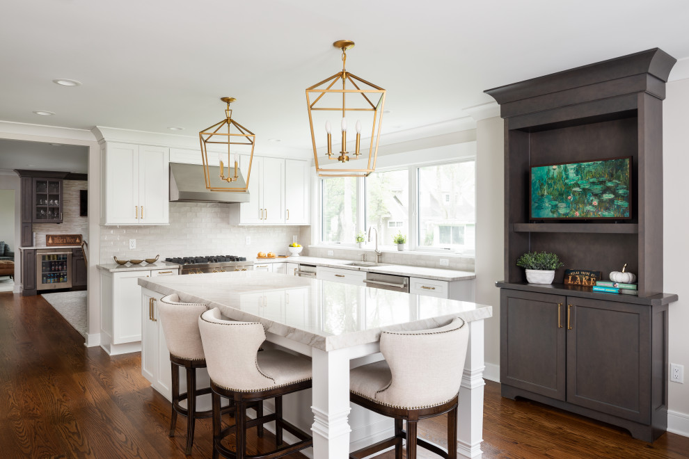 Example of a large classic medium tone wood floor kitchen design in New York with an undermount sink, shaker cabinets, quartzite countertops, beige backsplash, porcelain backsplash, stainless steel appliances and an island